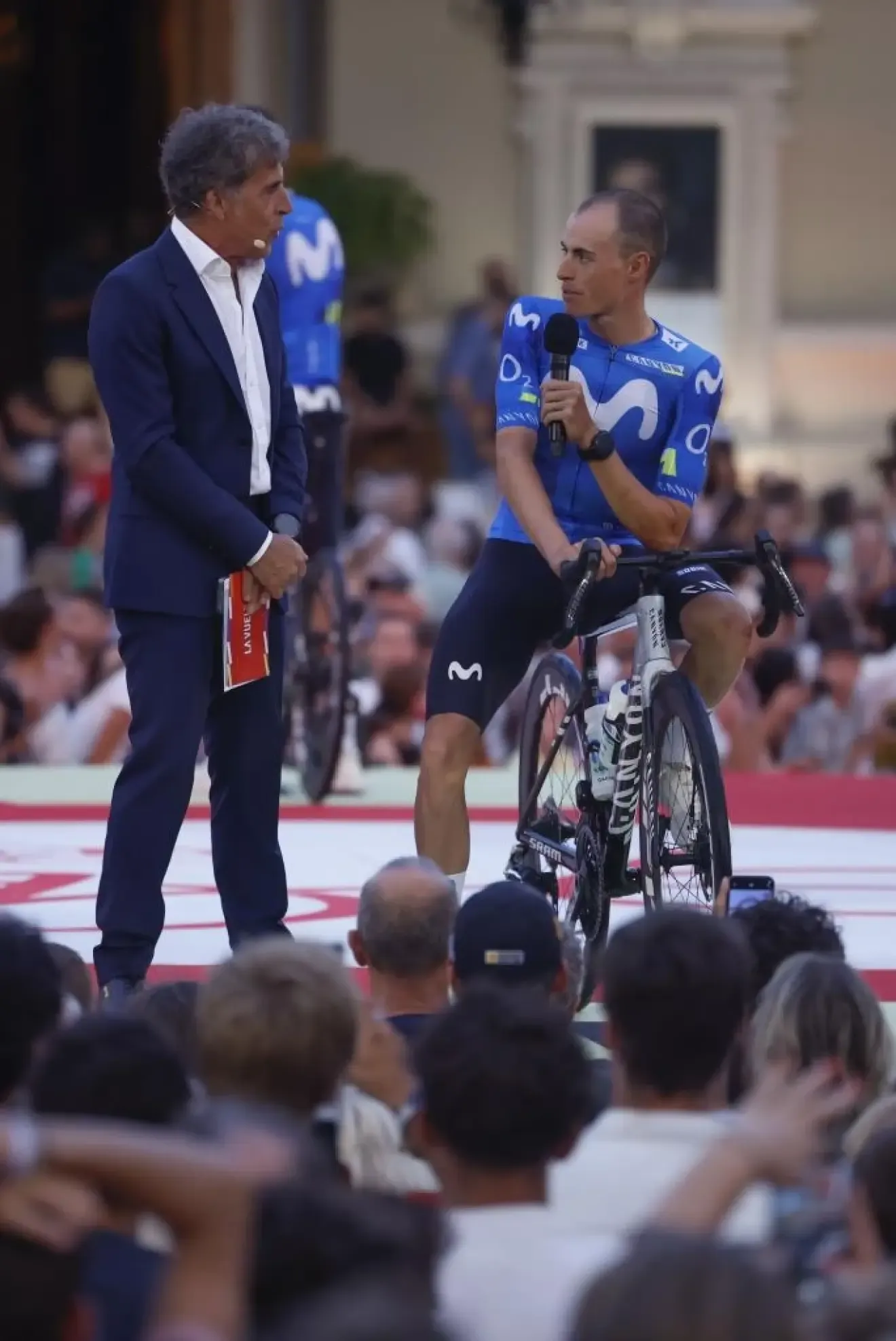 El ciclista Enric Mas, del equipo Movistar, conversa con Perico Delgado en Mónaco, donde este jueves tiene lugar la gala de presentación de los equipos de la Vuelta a España 2026, que comienza el sábado desde tierras monegascas.